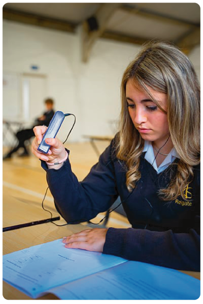 Studentessa in aula usa un lettore OrCam Read 3 per leggere un documento cartaceo.